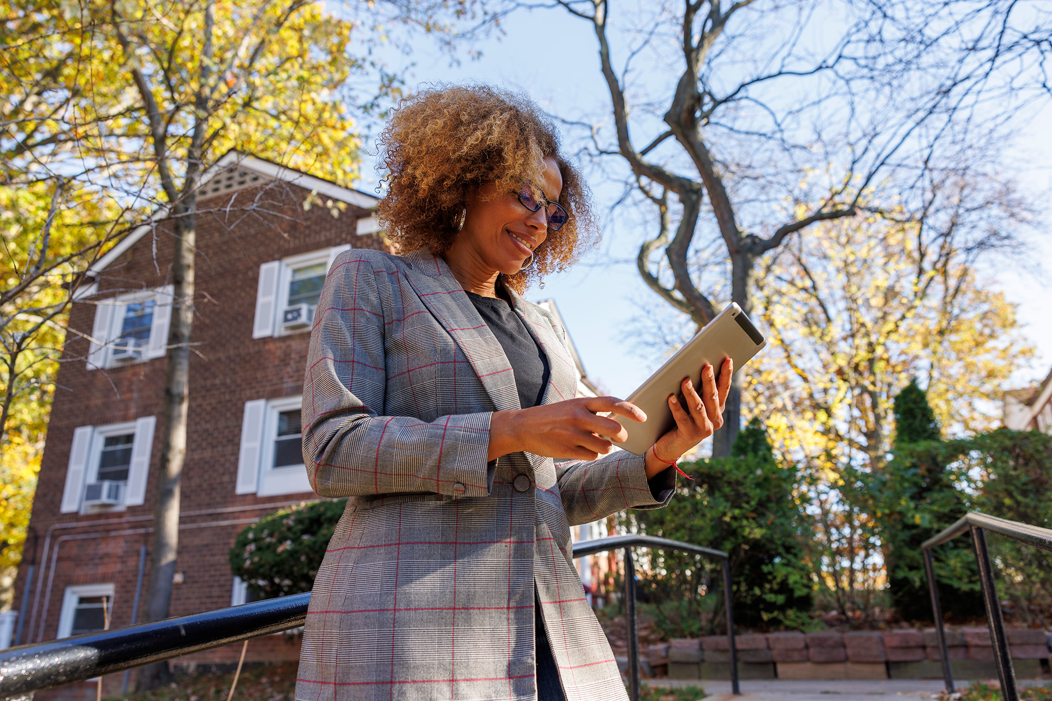 Woman looking at tablet in front of apartment building