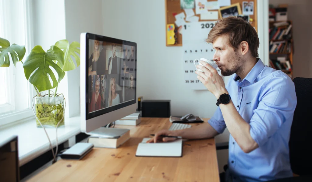Young man drinking coffee while having a video call on desktop